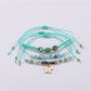 Detailed shot of butterfly shaped pendant and small gold beads on Lovra bracelet