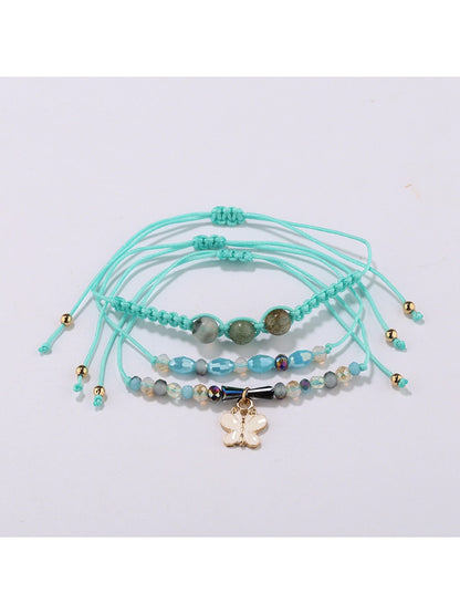 Detailed shot of butterfly shaped pendant and small gold beads on Lovra bracelet