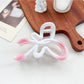 Beau heart shaped bow claw clip in ombre colors next to a ruler for size reference