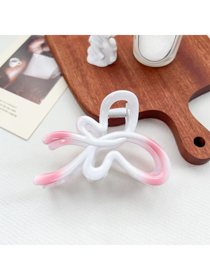 Beau heart shaped bow claw clip in ombre colors next to a ruler for size reference