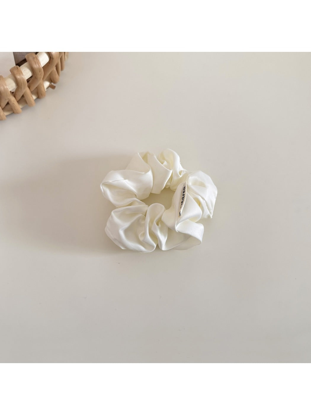 Beige satin bow scrunchie laid flat showing the elastic band inside
