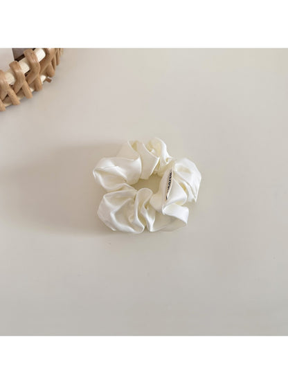 Beige satin bow scrunchie laid flat showing the elastic band inside
