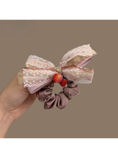 Close-up of Gifty Strawberry Charm Lace Bow Scrunchie with red strawberry charm and white lace bow
