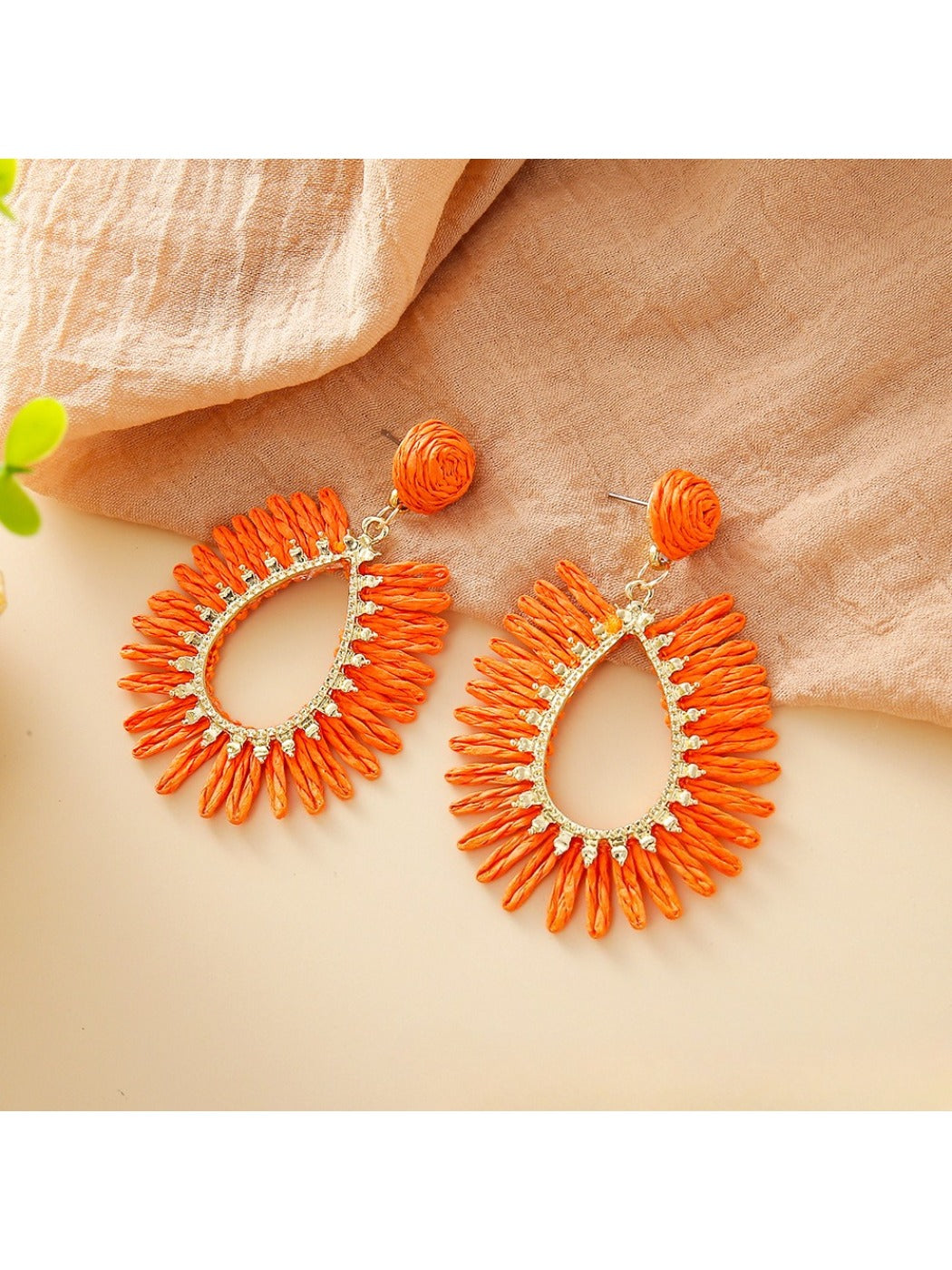 Side view of single raffia teardrop hollow earring showing woven texture