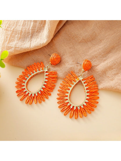 Side view of single raffia teardrop hollow earring showing woven texture