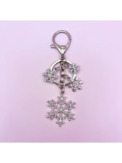 Snowflake pendant keychain resting on a textured fabric surface