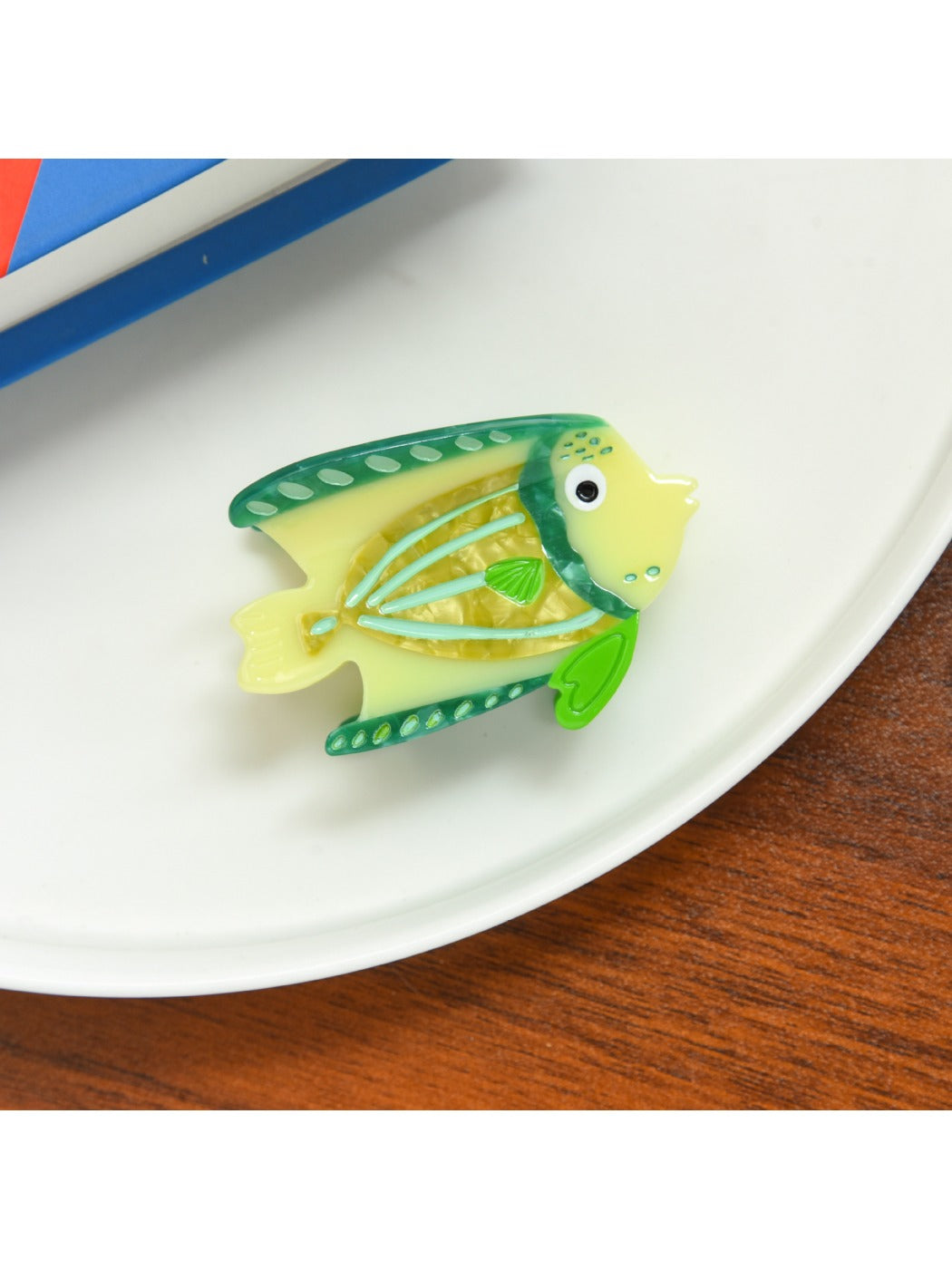 Beau tropical fish shaped hair clip displayed alongside tropical leaves for thematic styling