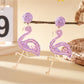 Flamingo pendant earrings packaged in a small jewelry box with a soft lining