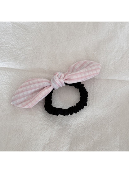Gifty plaid hair tie with red bow wrapped around a ponytail on a model