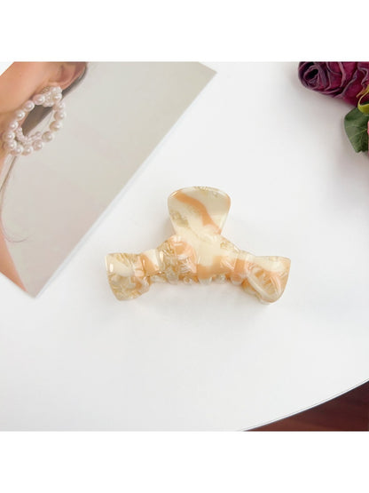 Beau bow shaped claw clip resting on a marble countertop