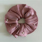 Elegant satin scrunchie paired with casual outfit on a wooden surface