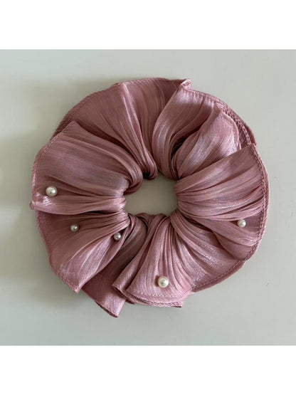 Elegant satin scrunchie paired with casual outfit on a wooden surface
