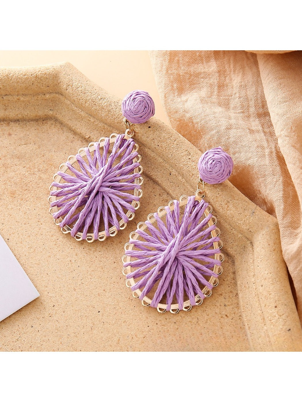 Close-up of earring hook and raffia weave pattern on teardrop shaped earrings