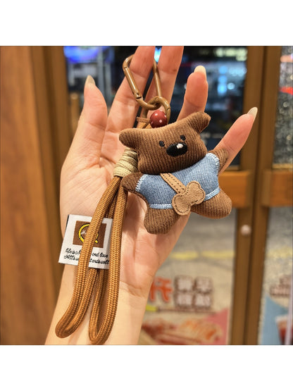 Fabric little bear keychain hanging from a backpack zipper