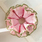 Close-up of pink lace scrunchie with delicate floral pattern on white background