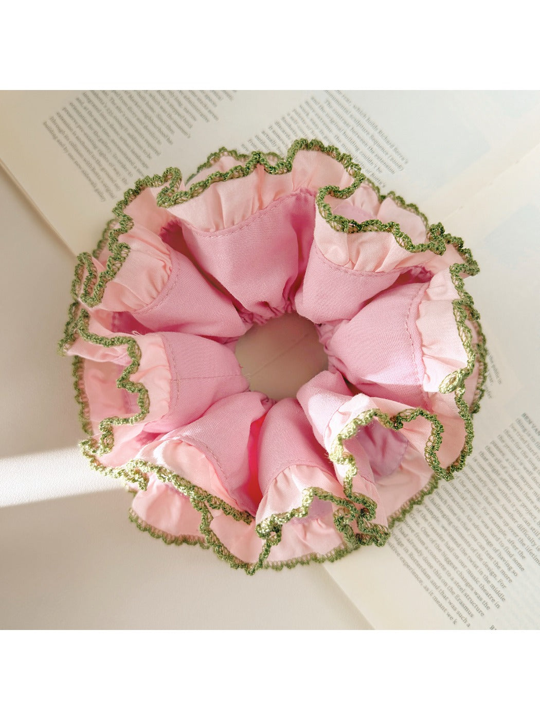 Close-up of pink lace scrunchie with delicate floral pattern on white background