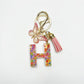 Keychain with butterfly and letter pendant resting on a leather wallet