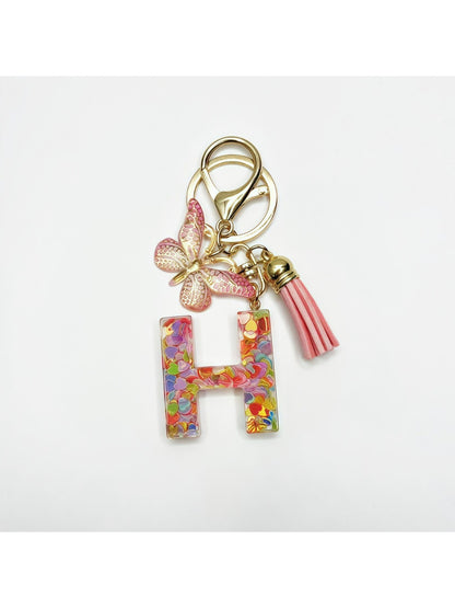 Keychain with butterfly and letter pendant resting on a leather wallet
