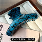 Beau claw clip placed on a wooden surface with natural lighting