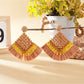 Vintage square raffia drop earrings placed on a wooden surface with soft shadows