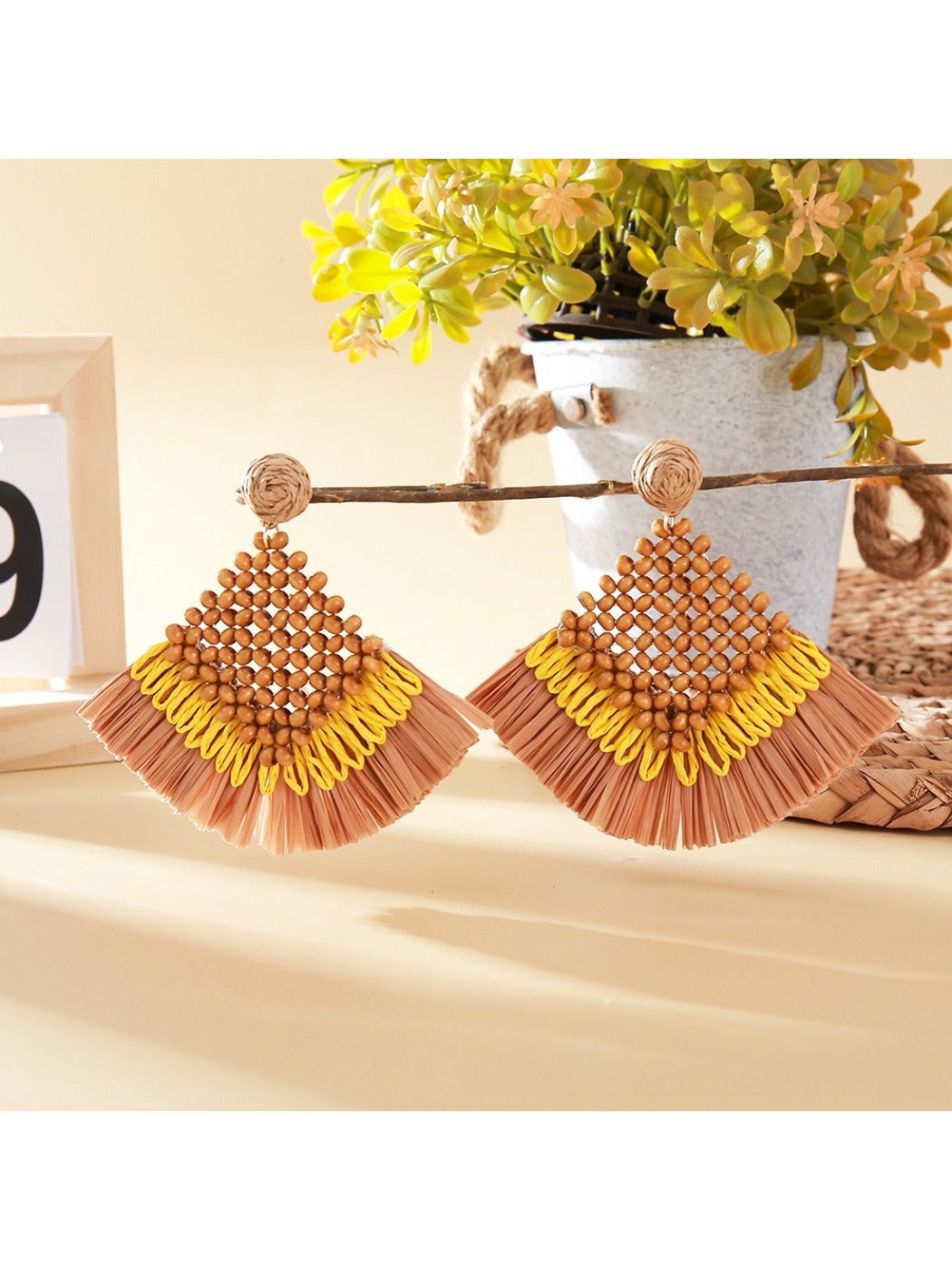 Vintage square raffia drop earrings placed on a wooden surface with soft shadows