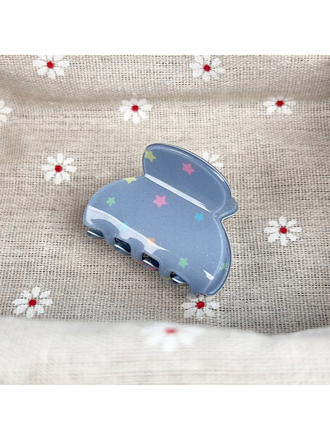 Beau hair claw clip with blue star design next to matching accessories
