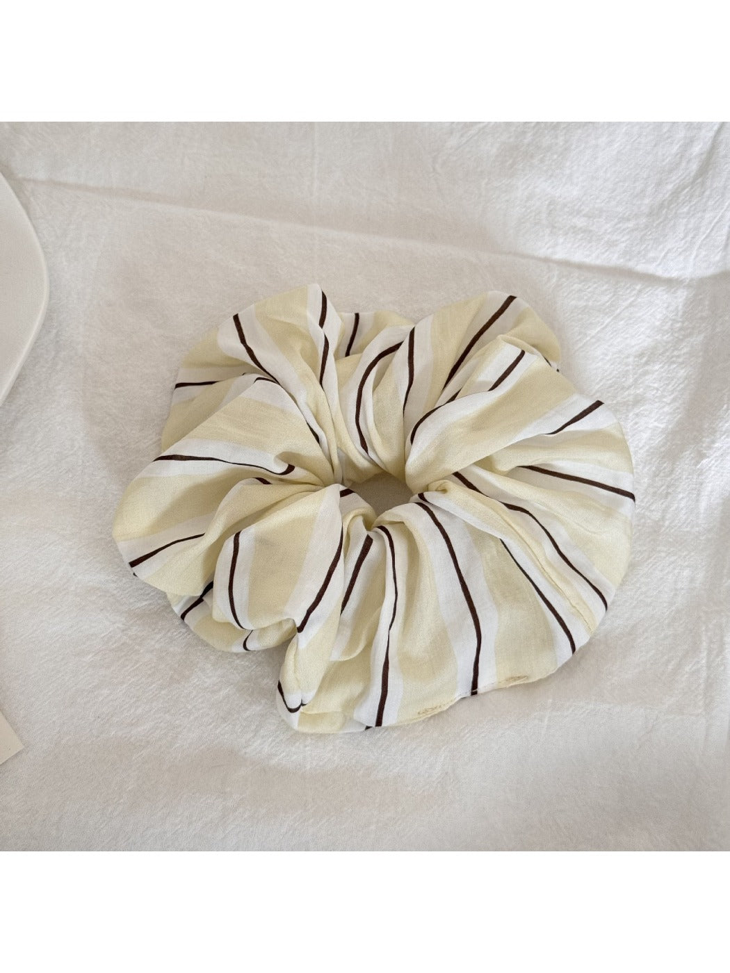 Yellow stripe print scrunchie styled on a wrist as an accessory