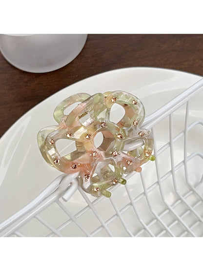 Beau hair claw clip with openwork flower pattern placed next to flowers