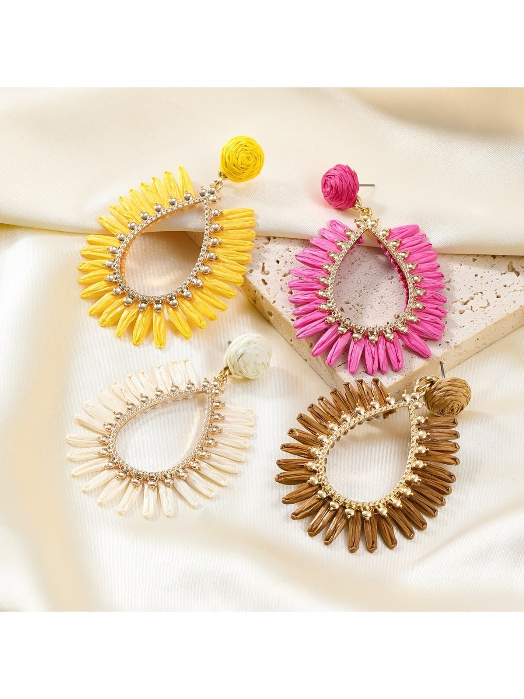 Side view of oval raffia drop earrings showing woven texture and gold hooks