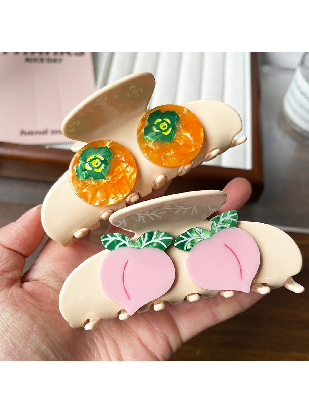 Beau claw clip shaped like an orange fruit held in hand