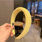 Yellow headband with bow shown from above on a neutral background