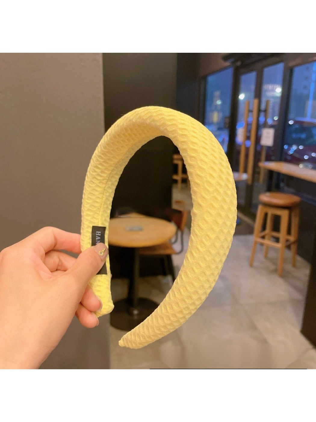 Yellow headband with bow shown from above on a neutral background