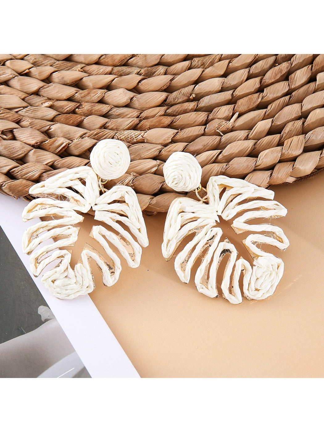 Side view of a single raffia woven hollow leaf shaped earring showing texture