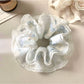Close-up of Gifty scrunchie showing smooth fabric texture and monochrome pattern