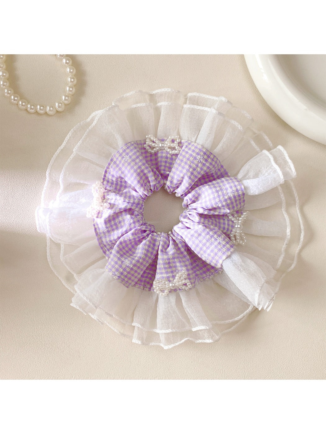 Gifty plaid bow scrunchie styled on a model's ponytail with soft lighting