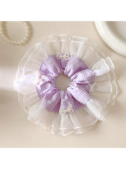 Gifty plaid bow scrunchie styled on a model's ponytail with soft lighting