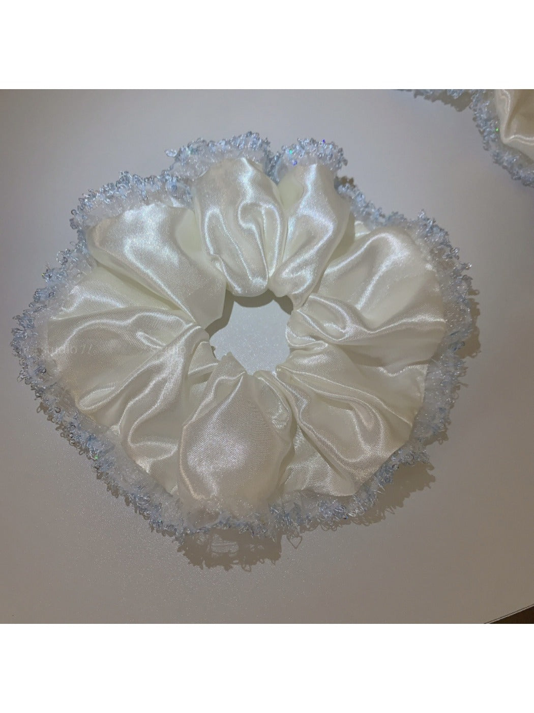 Satin white scrunchie with lace trim styled in a woman's hair