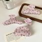 Close-up of Beau hair claw clip with pink rose pattern and curved teeth