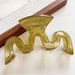 Beau hair claw clip in beige color on a wooden surface