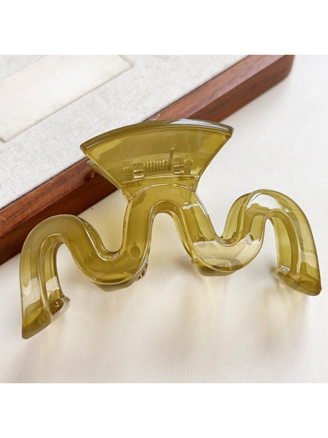 Beau hair claw clip in beige color on a wooden surface