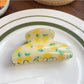 Beau fruit print shark claw clip resting on a wooden surface