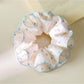 Pink fabric scrunchie featuring vibrant polka dot pattern laid flat