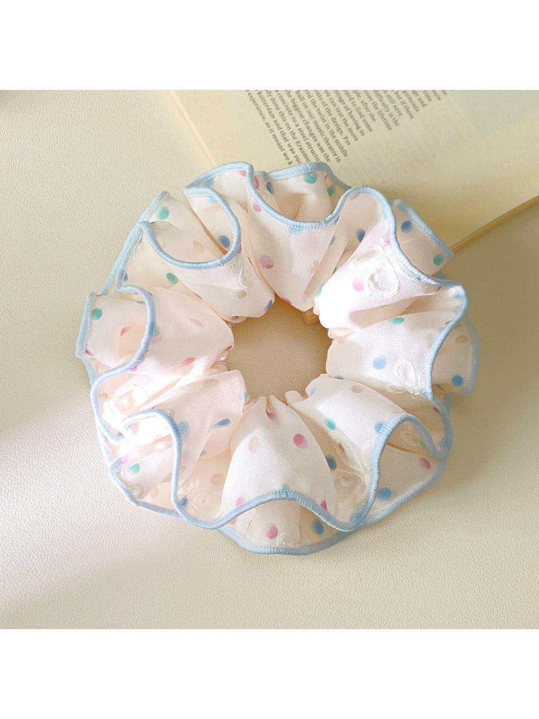 Pink fabric scrunchie featuring vibrant polka dot pattern laid flat