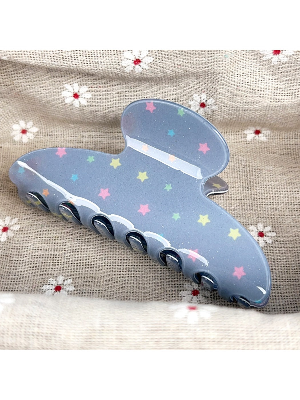 Top view of blue star print hair claw clip with glossy finish