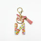Close-up of silver letter pendant with butterfly charm on keyring