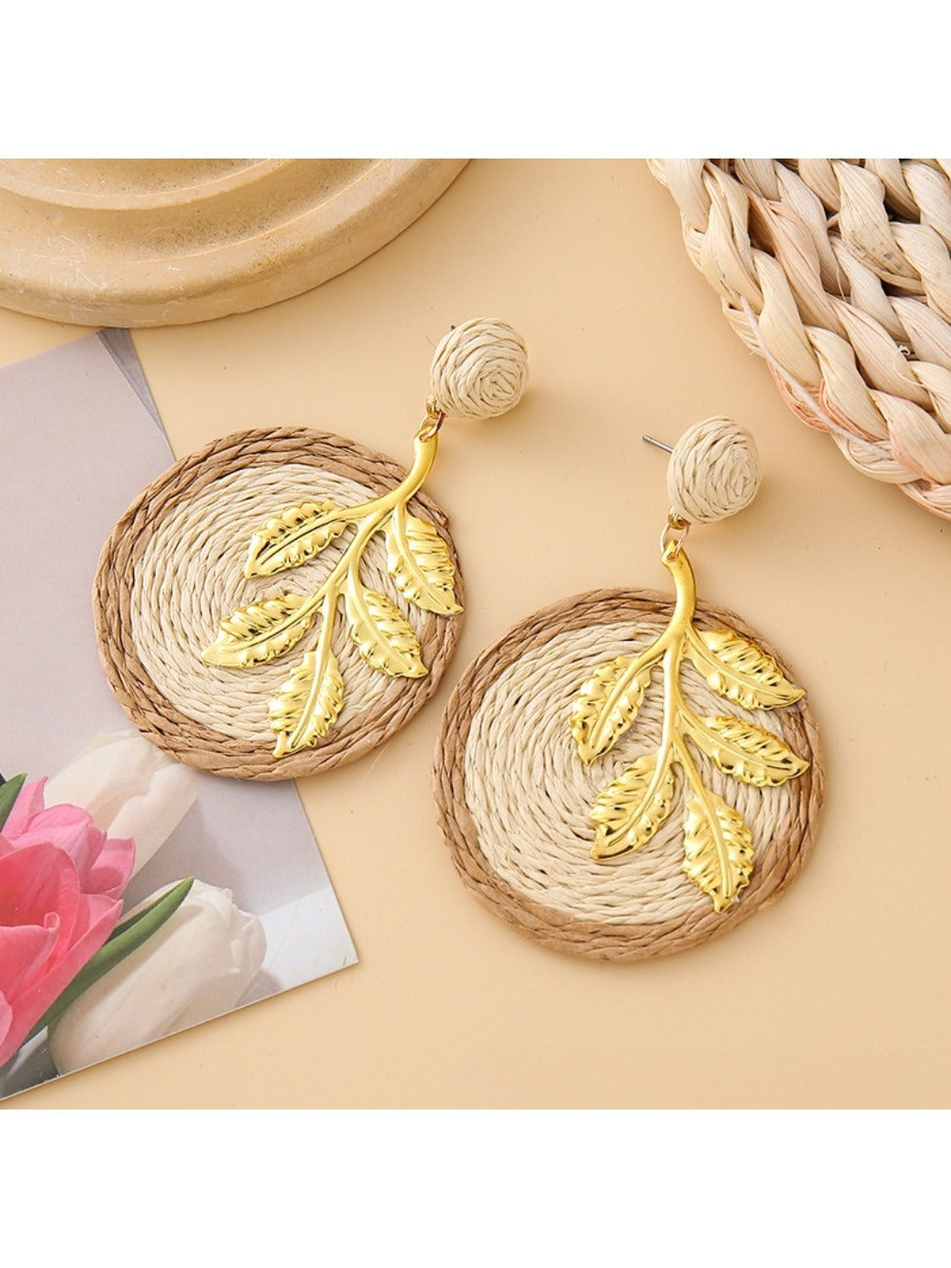 Earedge round leaf pendant earrings resting on a textured fabric