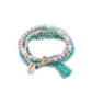 Detailed shot of Lovra bracelet tassel and gold bead accents on a neutral surface