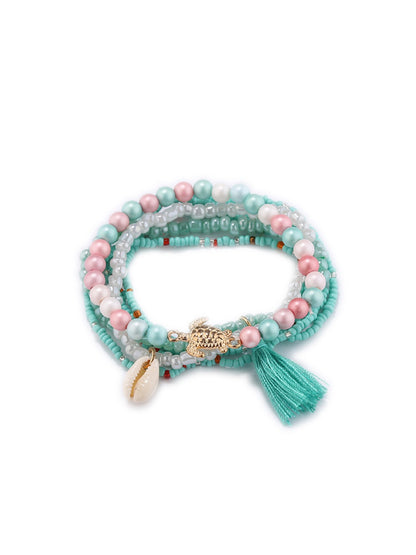 Detailed shot of Lovra bracelet tassel and gold bead accents on a neutral surface