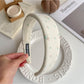 Gifty hair clip held in hand showing size and minimalist beige fabric design