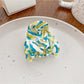 Beau half moon claw clip with vibrant multicolor design on neutral background